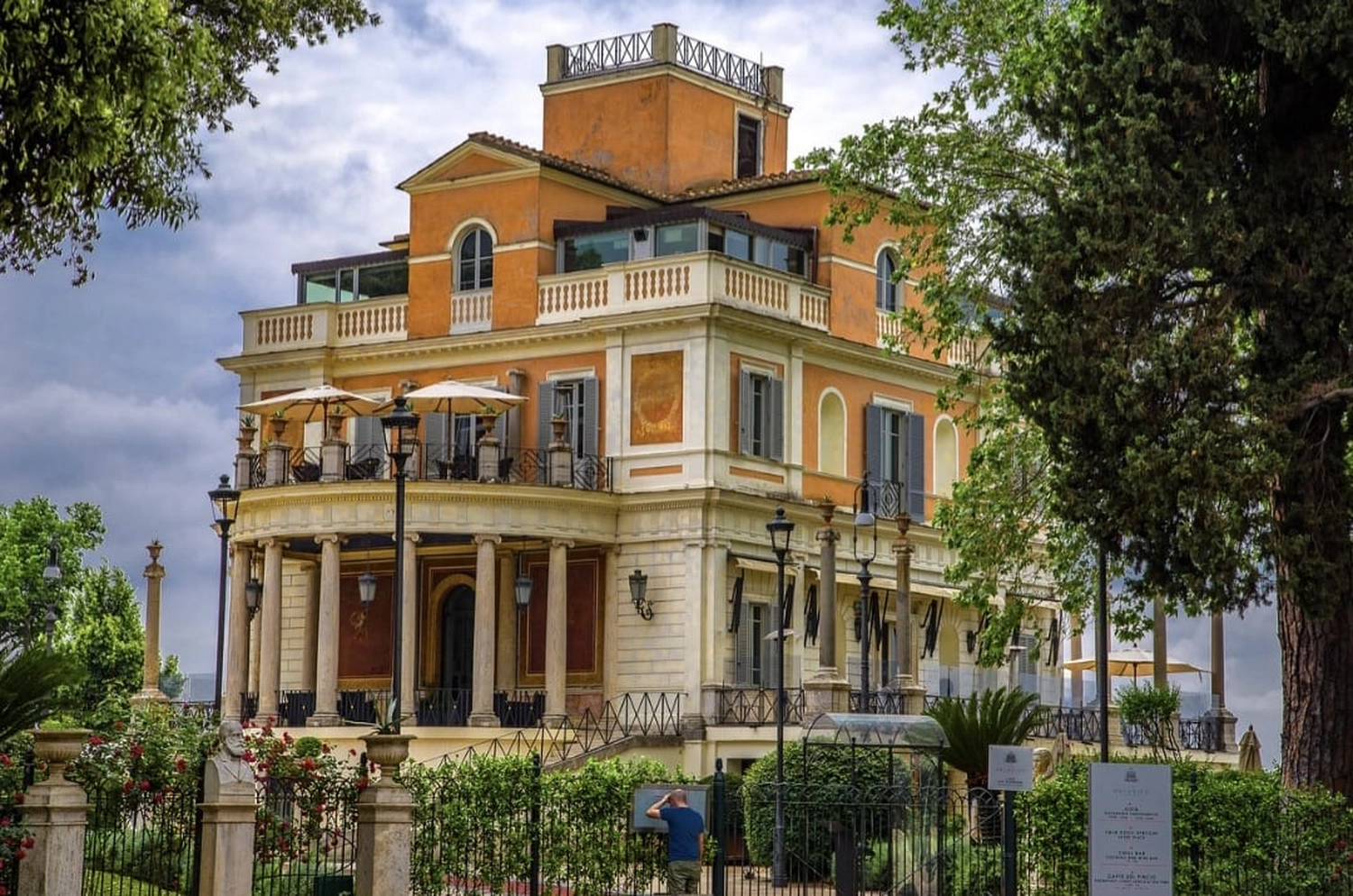 Haus & Handel – Immobilien – Stilvolles skandinavisches Wohnzimmer mit Designermöbeln, Pflanzen, Bambus-Bücherständer und Holzschreibtisch.